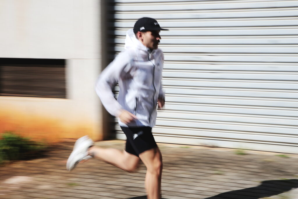 Homem correndo com corta vento branco e boné