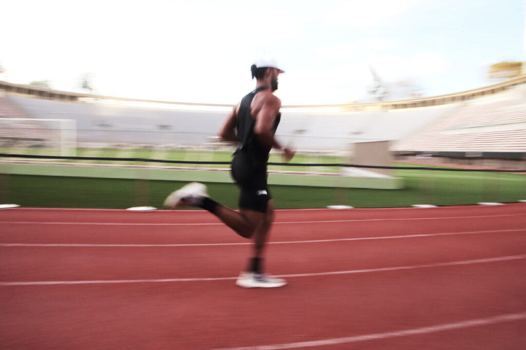HOMEM CORRENDO EM PISTA DE ATLETISMO